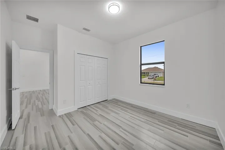 Room featuring wood-finish tile flooring, a bi-fold closet, a single-pane window with dark framing, and a flush-mount ceiling light