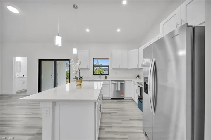 Kitchen featuring white cabinetry, an expansive center island with stone-finish countertops, stainless steel appliances, wood-finish flooring, and recessed lighting