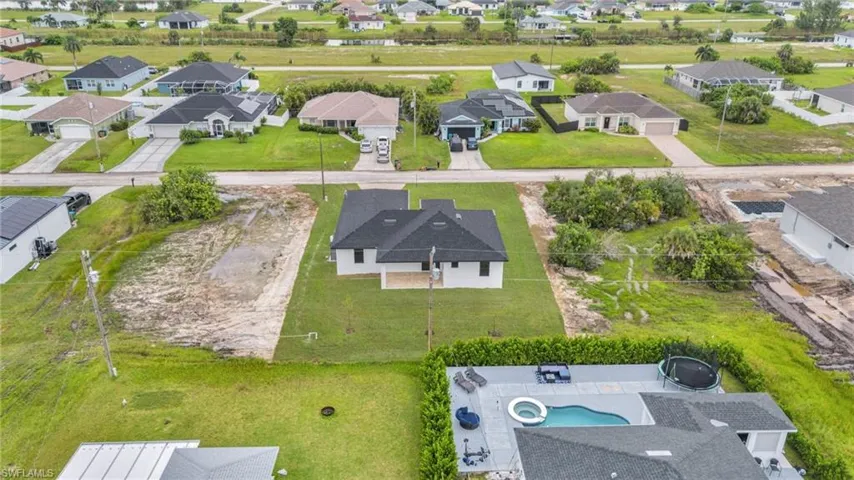 Aerial perspective featuring a single-family residence with a multi-gabled roof, integrated covered rear patio, and expansive grounds
