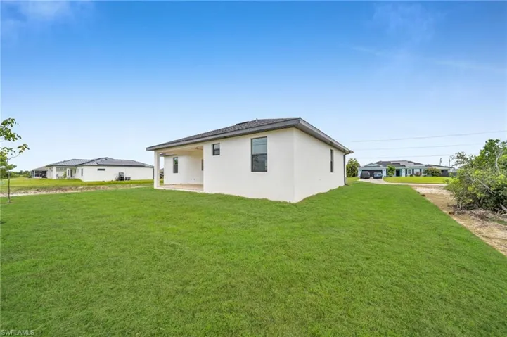 Exterior featuring a smooth stucco facade, hip roof with architectural shingles, covered rear patio, and expansive open yard space
