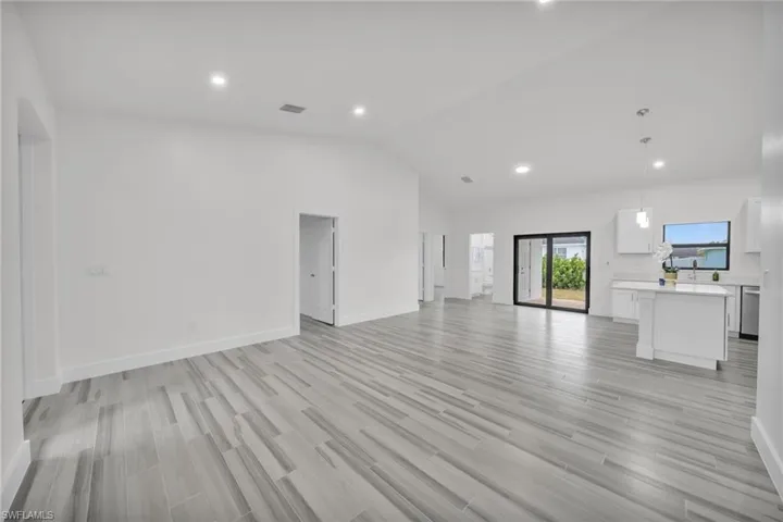 Open floor plan featuring vaulted ceilings, wood-finish tile flooring, recessed lighting, and a kitchen island with pendant lighting