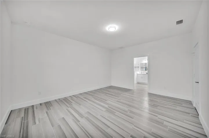 Room featuring wood-finish flooring, crisp white walls, and a recessed ceiling light fixture