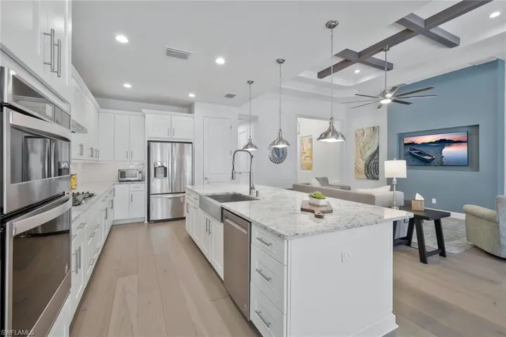 Kitchen featuring coffered ceiling, stainless steel appliances, light wood-type flooring, and a sink