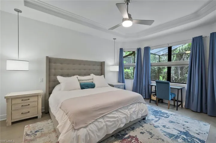 Bedroom with crown molding, a raised ceiling, and a ceiling fan
