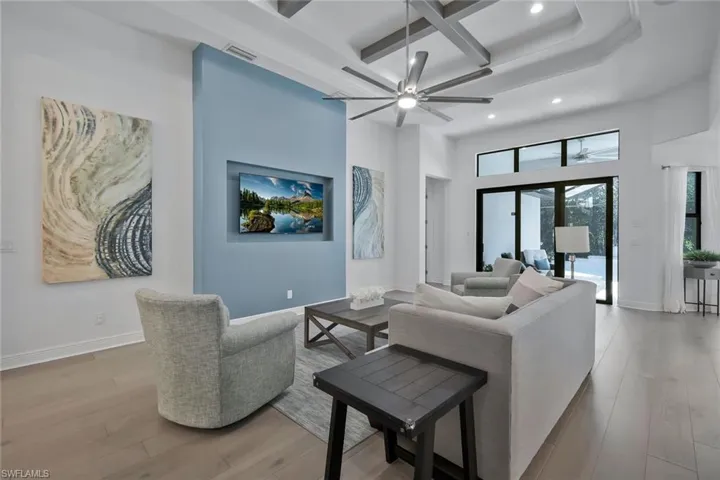 Living room with visible vents, baseboards, coffered ceiling, and wood finished floors