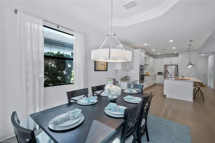 Dining area featuring a tray ceiling, light wood-style flooring, plenty of natural light, and recessed lighting