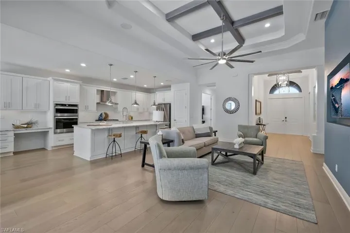 Living room with visible vents, coffered ceiling, and light wood-type flooring