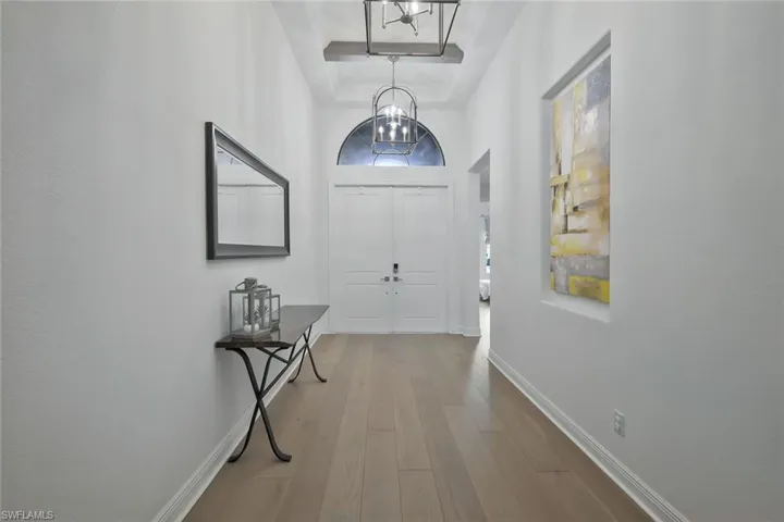 Foyer with baseboards, wood finished floors, a high ceiling, and a chandelier