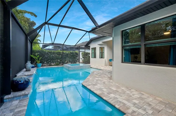 View of pool with a patio area, a lanai, and a pool with connected hot tub
