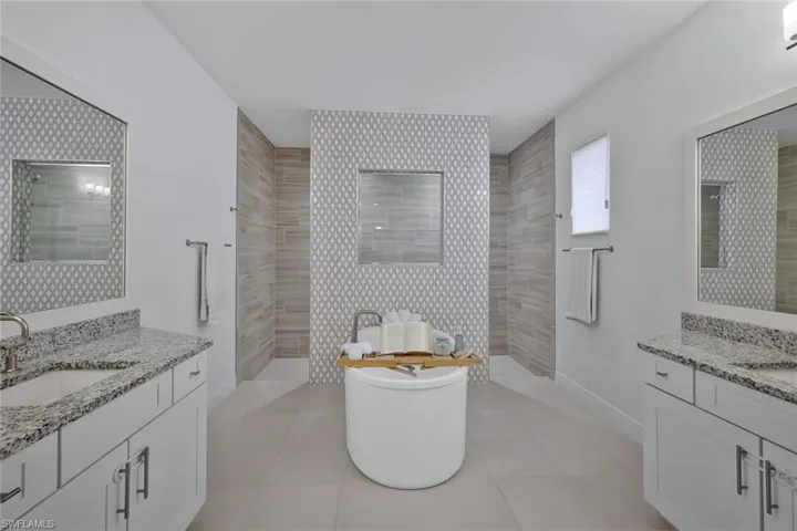 Bathroom featuring tile patterned flooring, a soaking tub, walk in shower, and a sink