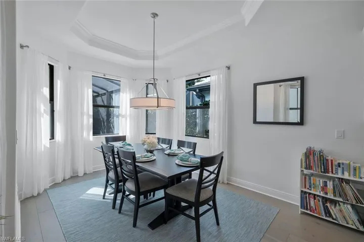 Dining area featuring baseboards, a raised ceiling, wood finished floors, and crown molding