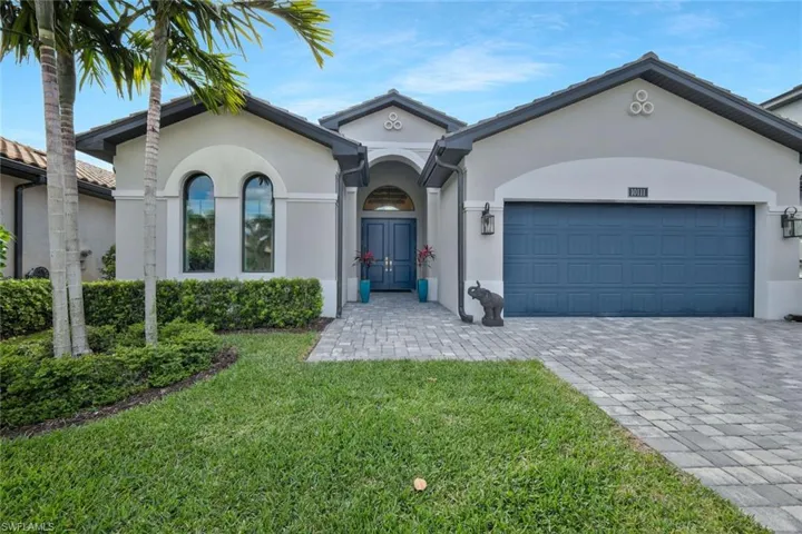 View of front of property featuring stucco siding, decorative driveway, a front yard, and an attached garage