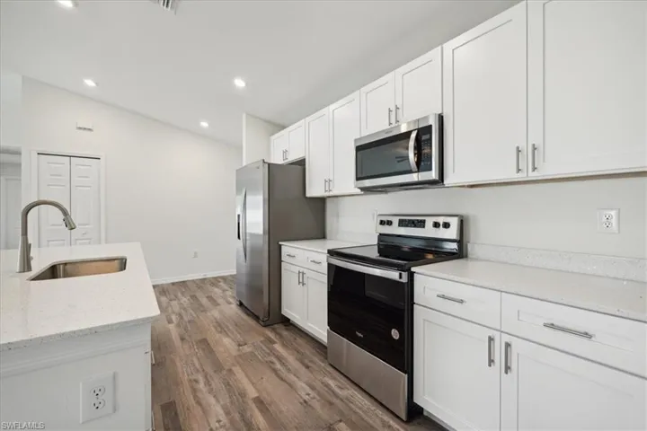 Kitchen featuring white cabinets, sink, dark wood-type flooring, and stainless steel appliances