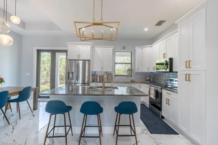 Kitchen with appliances with stainless steel finishes, a sink, tasteful backsplash, a breakfast bar, and recessed lighting