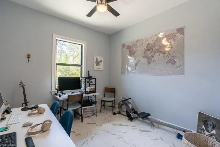 Office space with a ceiling fan and marble finish flooring