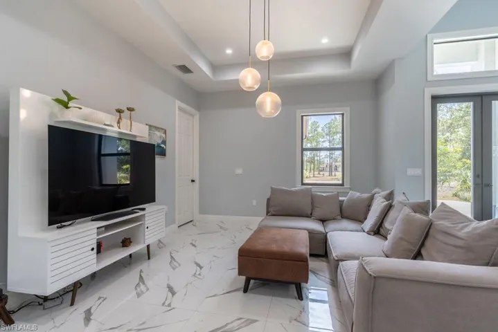 Living room featuring light marble finish floors, a tray ceiling, recessed lighting, and baseboards