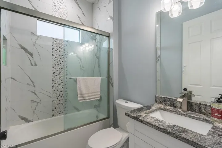 Full bathroom featuring bath / shower combo with glass door, toilet, and vanity