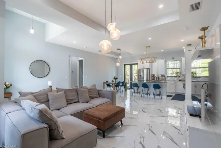 Living room featuring light marble finish flooring, recessed lighting, and a raised ceiling