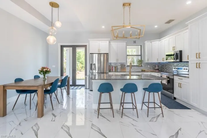 Kitchen with appliances with stainless steel finishes, tasteful backsplash, a kitchen bar, white cabinetry, and recessed lighting