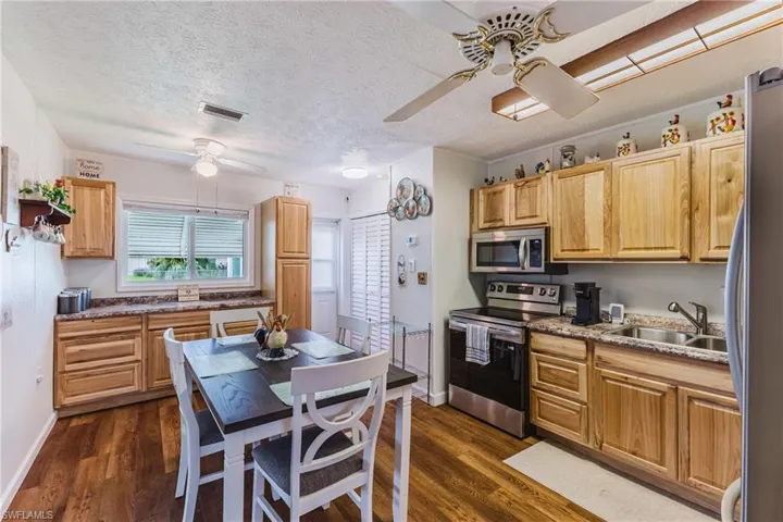 Kitchen featuring wood-finish flooring, wood cabinetry, stainless steel appliances, and a ceiling fan