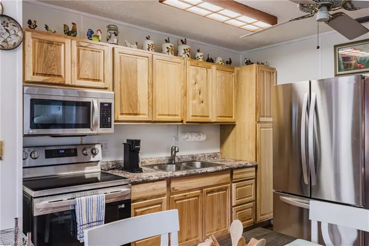Kitchen featuring wood-finish cabinetry, stainless steel appliances, a double basin sink, and laminate countertops