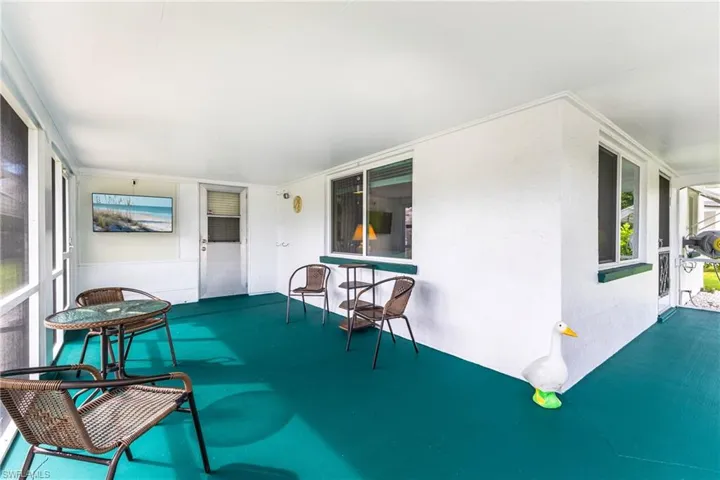 Spacious screened porch with a painted concrete floor, multiple windows, and exterior door