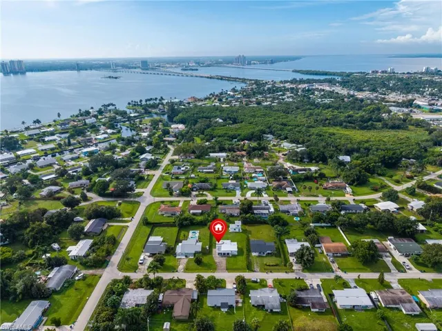 Aerial perspective of residential community with water frontage, mature trees, and street grid