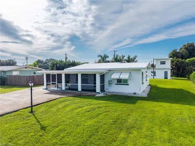 Single-story residence with a white exterior, screened-in front porch, metal roof, and a concrete driveway