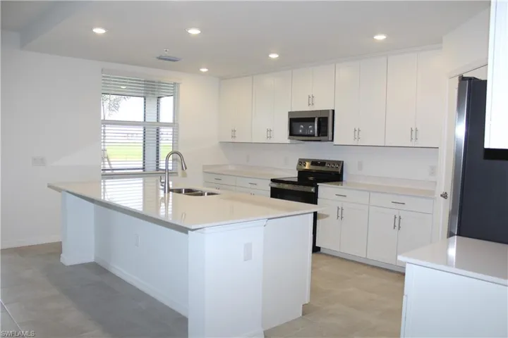 Kitchen with an island with sink, white cabinetry, a sink, and stainless steel appliances