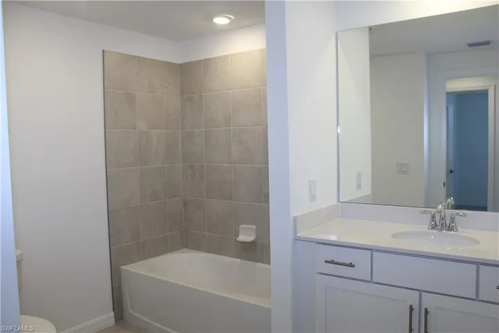 Guest bath with vanity, toilet, baseboards, visible vents, and washtub / shower combination