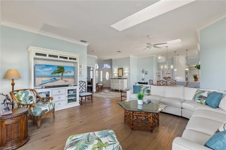 Living room featuring a skylight, ceiling fan, hardwood / wood-style floors, and ornamental molding