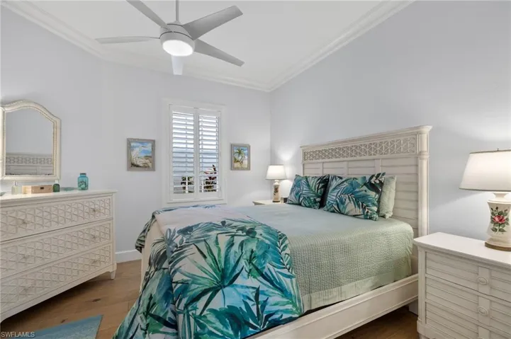 Bedroom with hardwood / wood-style floors, ceiling fan, and crown molding