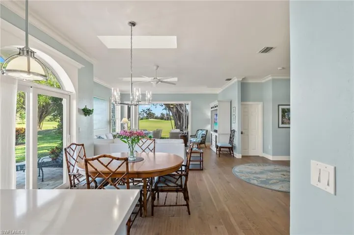 Dining space with a skylight, wood-type flooring, ceiling fan with notable chandelier, and ornamental molding