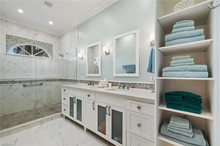 Bathroom featuring a tile shower, vanity, tile walls, and crown molding