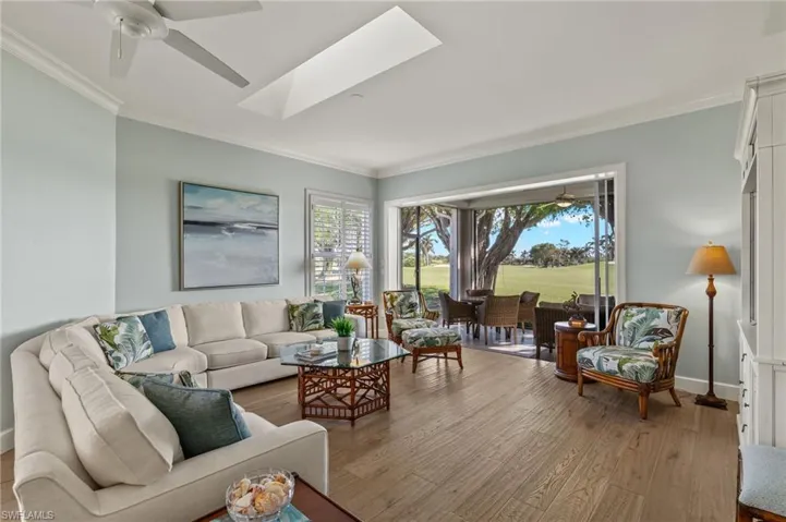 Living room featuring ceiling fan, crown molding, light hardwood / wood-style flooring, and a skylight