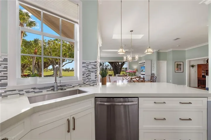 Kitchen with sink, stainless steel dishwasher, pendant lighting, decorative backsplash, and white cabinets