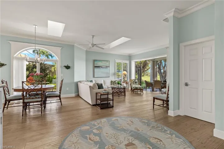 Living room with crown molding, hardwood / wood-style floors, a healthy amount of sunlight, and ceiling fan with notable chandelier