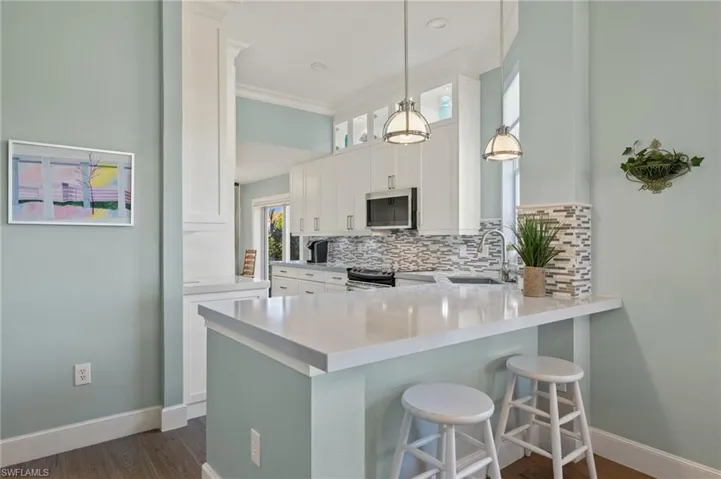 Kitchen featuring white cabinets, sink, stainless steel appliances, and hanging light fixtures