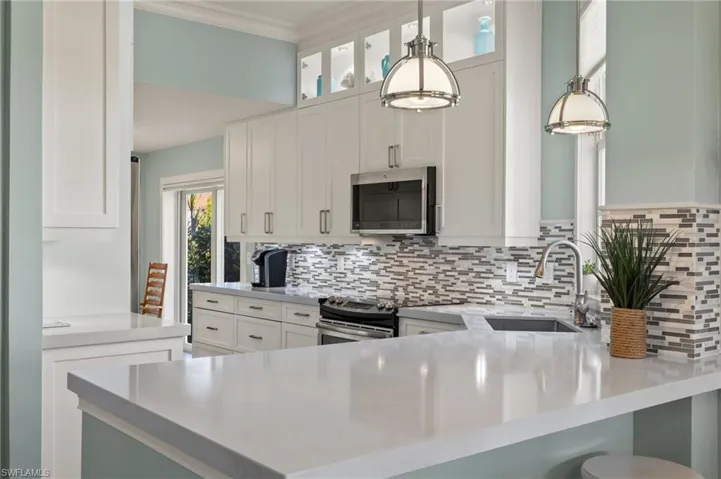 Kitchen with white cabinets, appliances with stainless steel finishes, tasteful backsplash, and sink