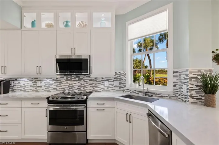 Kitchen with white cabinets, appliances with stainless steel finishes, tasteful backsplash, and sink