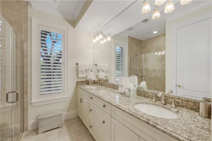 En suite guest bathroom with walk-in shower and two separate sinks.