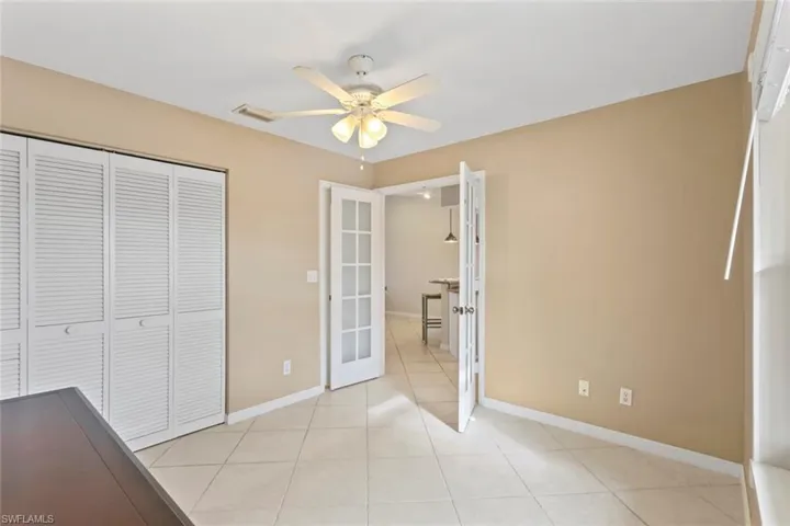 Unfurnished bedroom featuring light tile patterned floors, a ceiling fan, a closet, and french doors