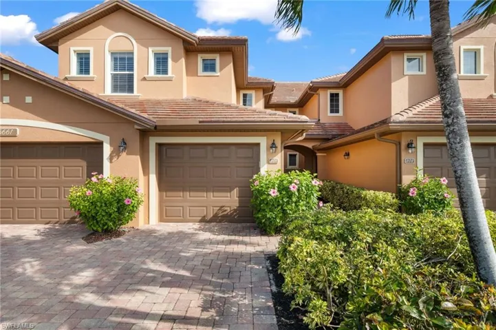 View of front of property featuring a tiled roof, decorative driveway, and stucco siding