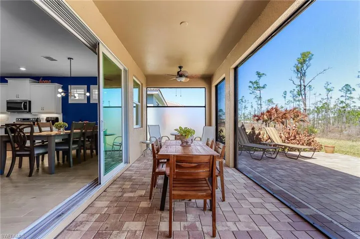 Expansive covered patio featuring paver flooring, a ceiling fan, and large sliding glass doors