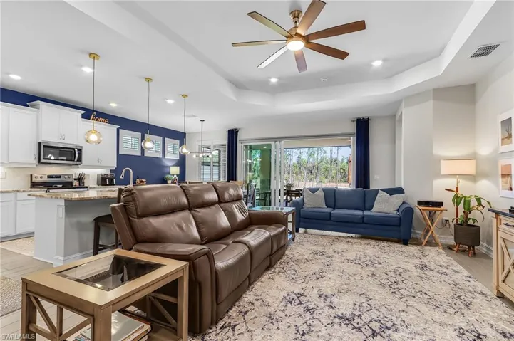 Open-concept living space featuring a tray ceiling, recessed lighting, and a ceiling fan