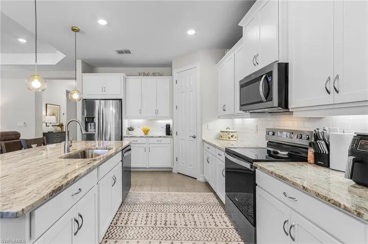 Modern kitchen featuring white cabinetry, light-toned countertops, stainless steel appliances, and wood-finish flooring