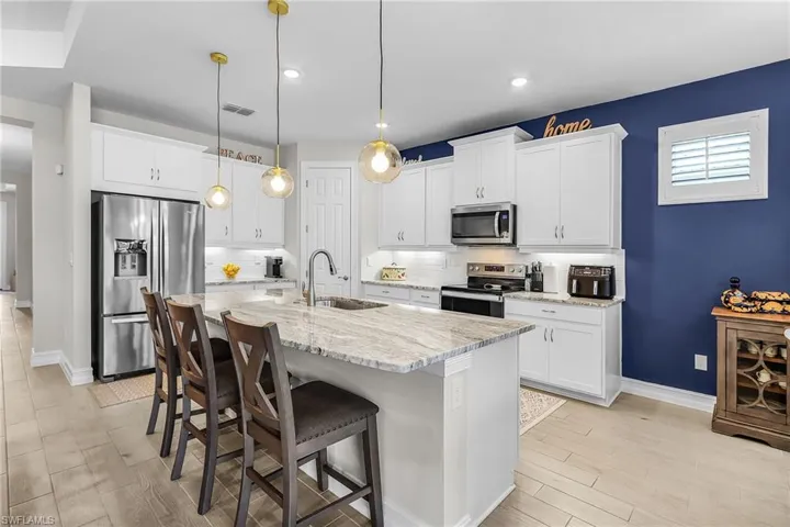 Modern kitchen featuring a large central island with a stone countertop and seating for four