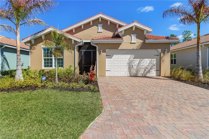 Mediterranean-style residence featuring a tile roof, stucco exterior, and a paver driveway