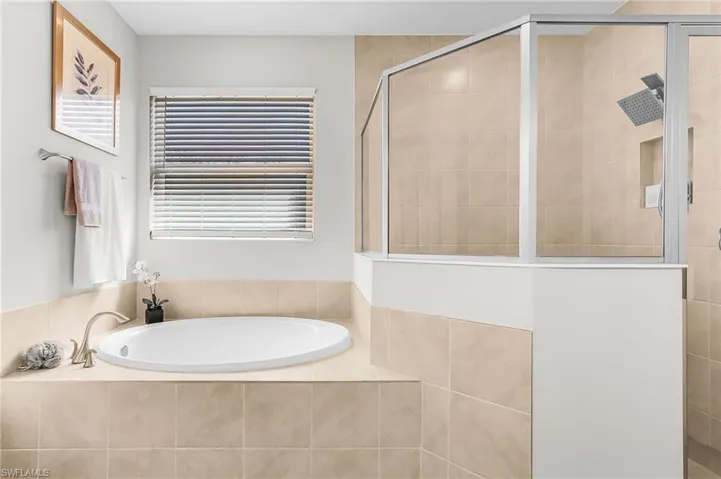 Built-in soaking tub with brushed nickel fixtures and surrounding tiled enclosure