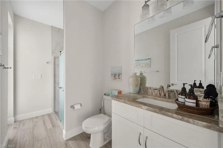 Bathroom featuring a shower, hardwood / wood-style floors, vanity, and toilet